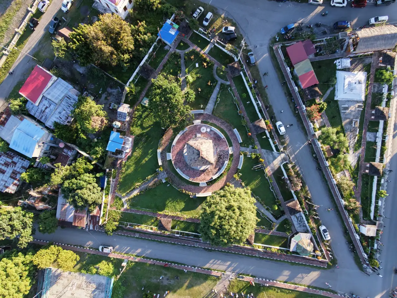Aerial view of a Timorese community centred on a circular public square, surrounded by gardens, homes and tree-lined streets.